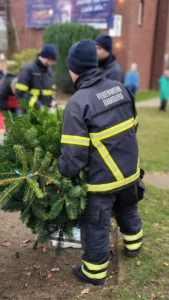 Eine Person in Feuerwehruniform hält einen Tannenbaum in den Händen.