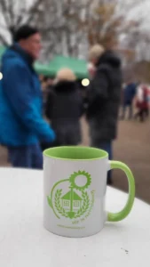 Ein Glühweinbecher mit Aufdruck des ARGE-Logos, steht auf einem Tisch.