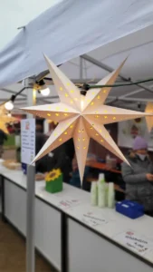 Ein leuchtender Weihnachtsstern hängt an einer Weihnachtsmarktbude.